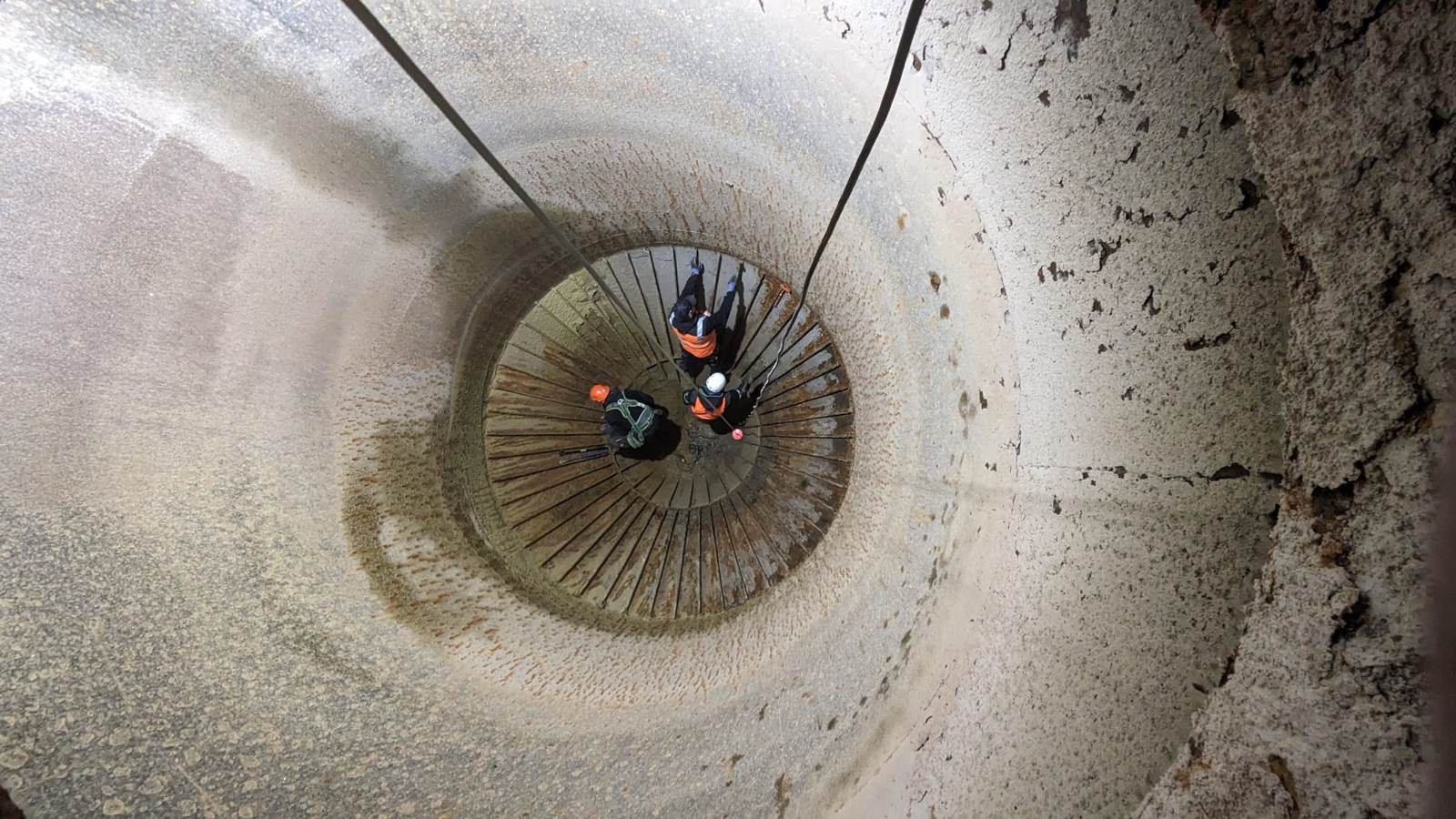Stark korrodiertes Silo-Inneres vor der Sanierung, zwei Techniker bei der Begutachtung